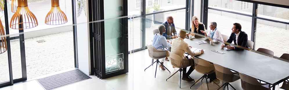 office space with a conference table full of people sitting around it talking