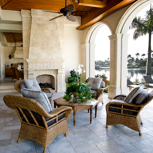 Elevated aesthetic outdoor patio with fireplace, ceiling fan, furniture and arches overlooking a pool