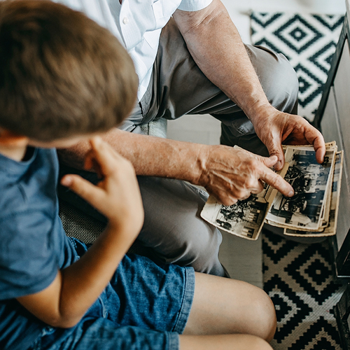 older man sitting with a young boy showing him pictures