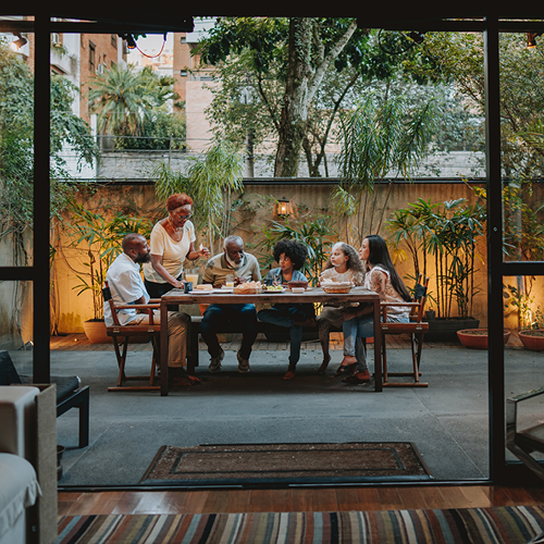 family sitting outside on patio at big table for dinner