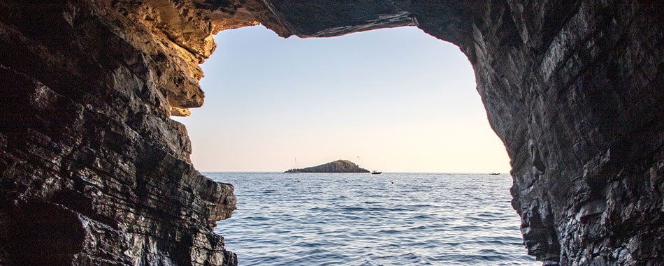 Looking out from inside cave towards ocean and small island piece of land in the distance