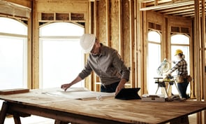 Architect looking over blueprints at home construction site