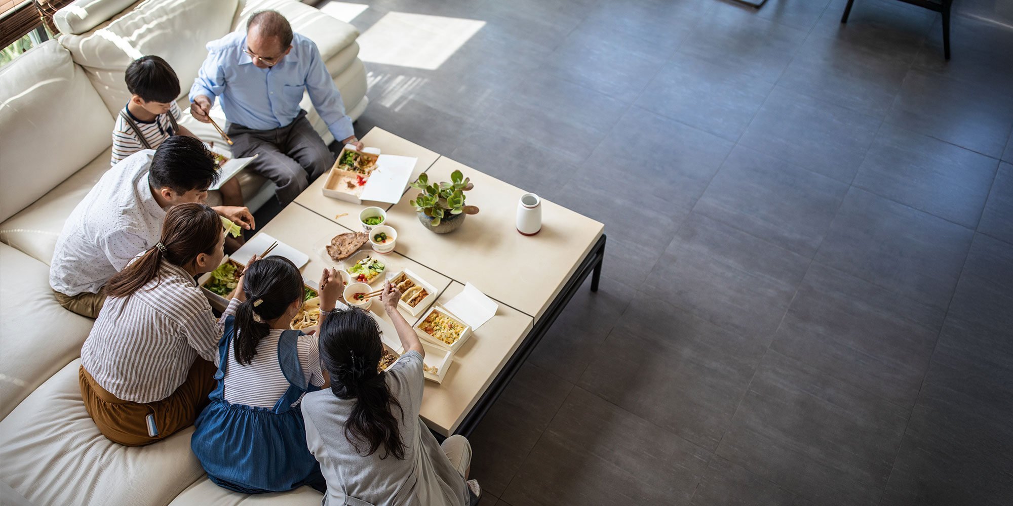Taiwanese grandparents, parents and children sitting in modern living room at home,having lunch together , high angle view