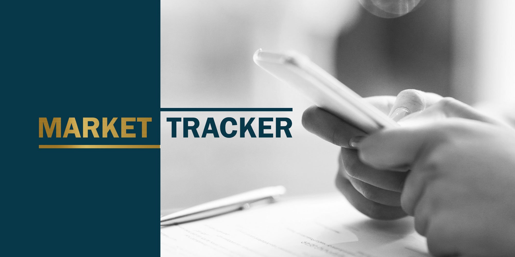 Market tracker, hand holding phone on desk 