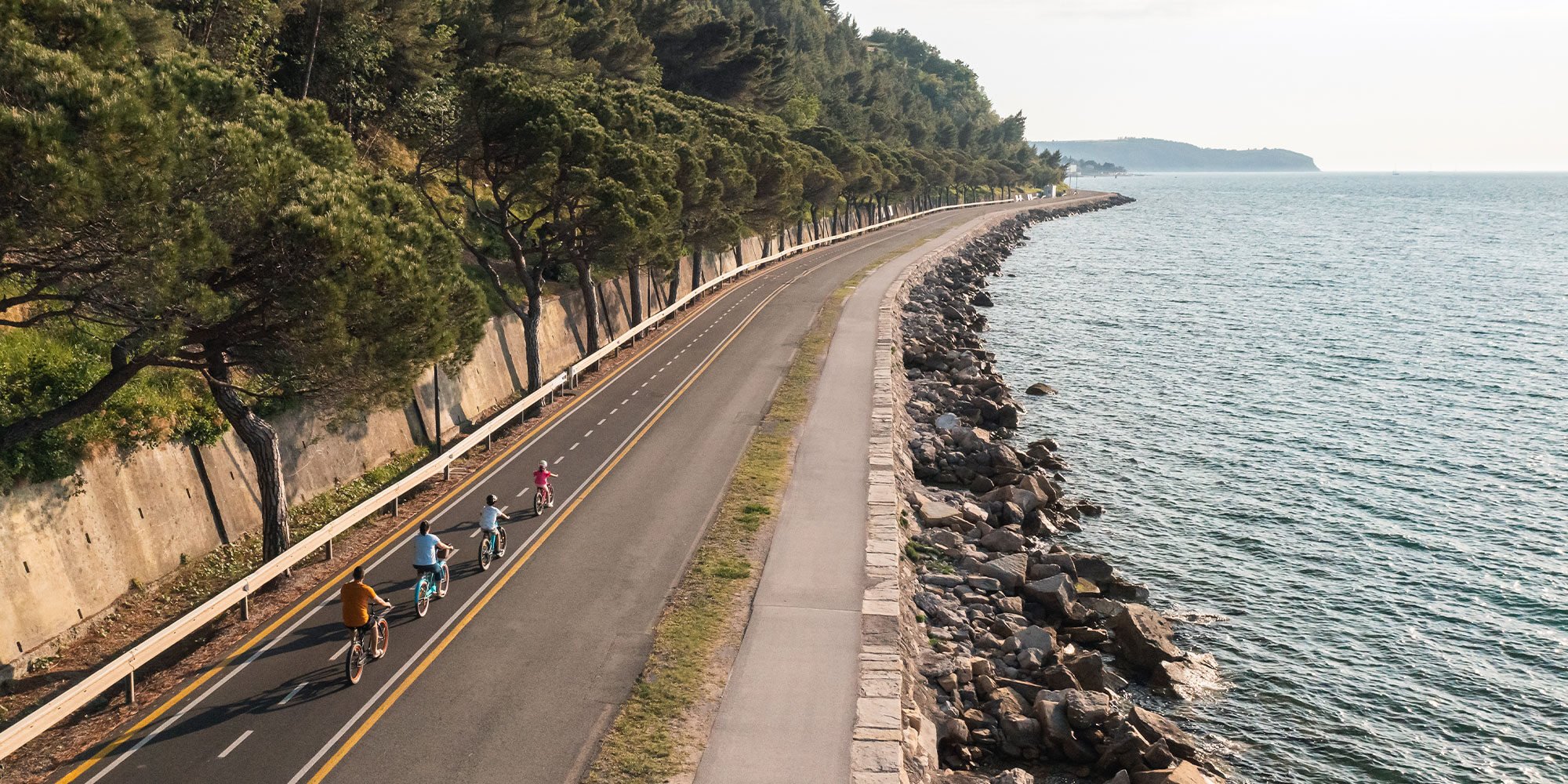 Family of four enjoying in together cycling near the sea