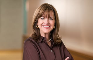 Headshot of Commerce Trust's Angie Ackerman in an office setting wearing a brown blouse with earrings and a necklace